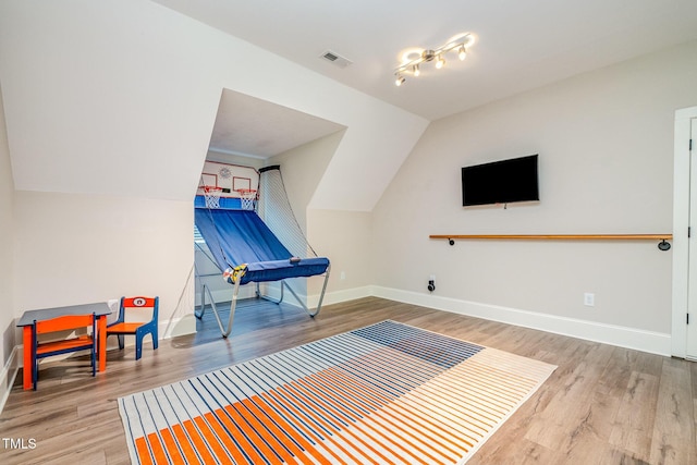 game room with baseboards, visible vents, track lighting, vaulted ceiling, and wood finished floors