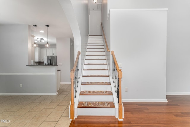 stairs with recessed lighting, baseboards, arched walkways, and wood finished floors