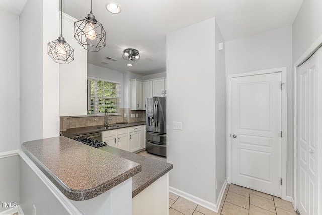 kitchen with stainless steel refrigerator with ice dispenser, a sink, decorative backsplash, and white cabinets