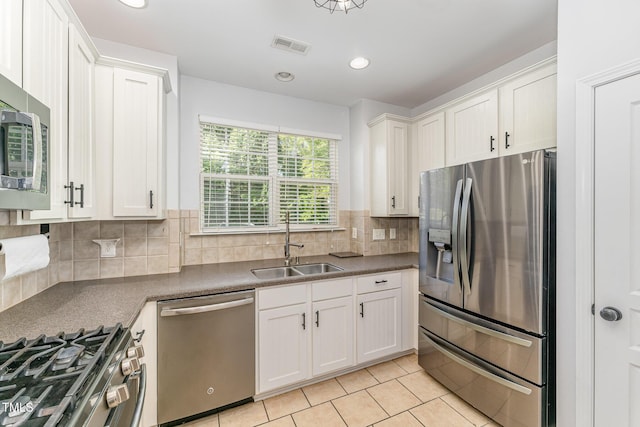 kitchen featuring stainless steel appliances, light tile patterned floors, white cabinetry, and a sink