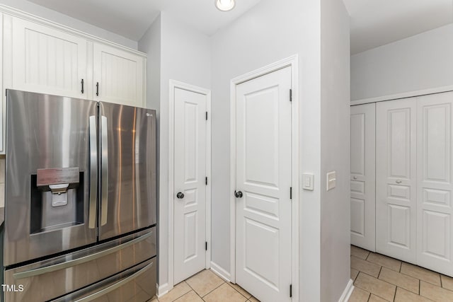 kitchen featuring white cabinetry, baseboards, light tile patterned floors, and stainless steel fridge with ice dispenser