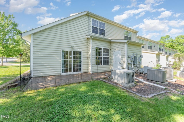 rear view of house with central AC unit and a yard