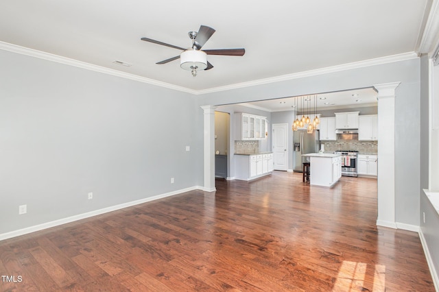 unfurnished living room with baseboards, ornamental molding, ceiling fan with notable chandelier, and decorative columns