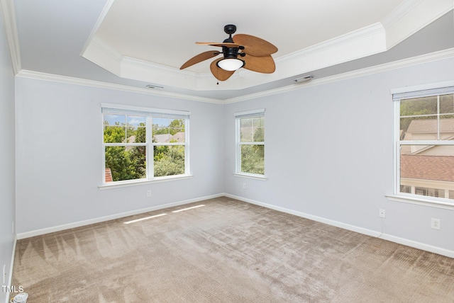 carpeted empty room with baseboards, a tray ceiling, ceiling fan, and crown molding