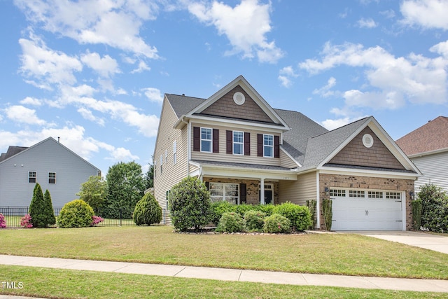 craftsman house with fence, a front lawn, concrete driveway, brick siding, and a garage
