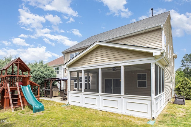 rear view of house with a sunroom, a yard, roof with shingles, and a playground