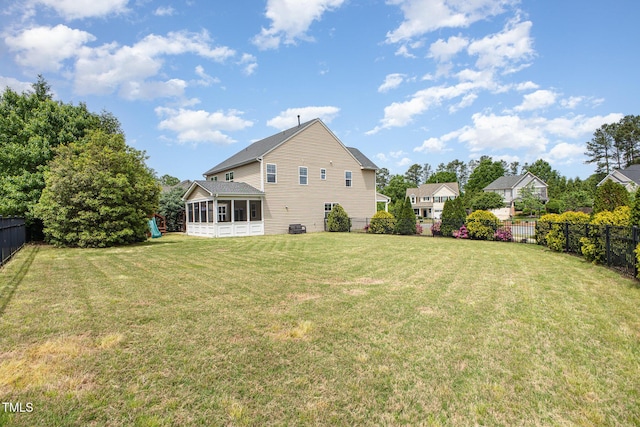 rear view of property with a lawn, a fenced backyard, and a sunroom