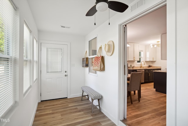 entryway featuring light wood-style floors, healthy amount of natural light, ceiling fan, and a chandelier