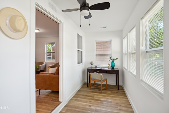 hallway featuring light wood-style flooring, baseboards, and built in shelves