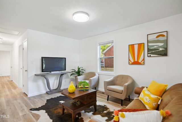 living room with light wood finished floors, attic access, and baseboards
