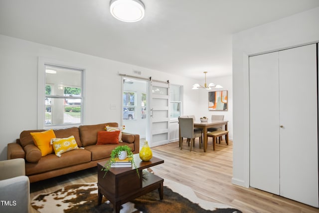 living area featuring a barn door, light wood-style flooring, and a chandelier