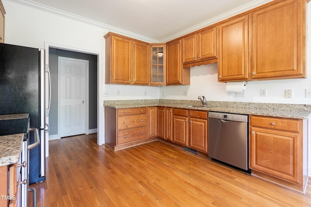 kitchen with light stone counters, a sink, light wood-style floors, stainless steel appliances, and brown cabinetry