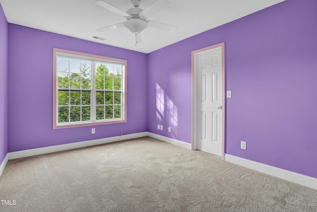 carpeted spare room featuring a ceiling fan, visible vents, and baseboards
