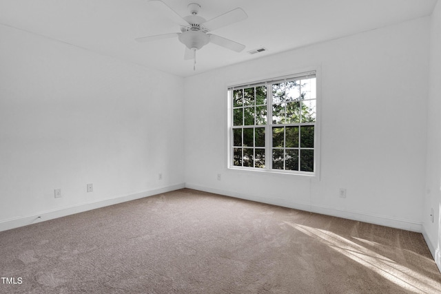empty room featuring carpet flooring, visible vents, ceiling fan, and baseboards