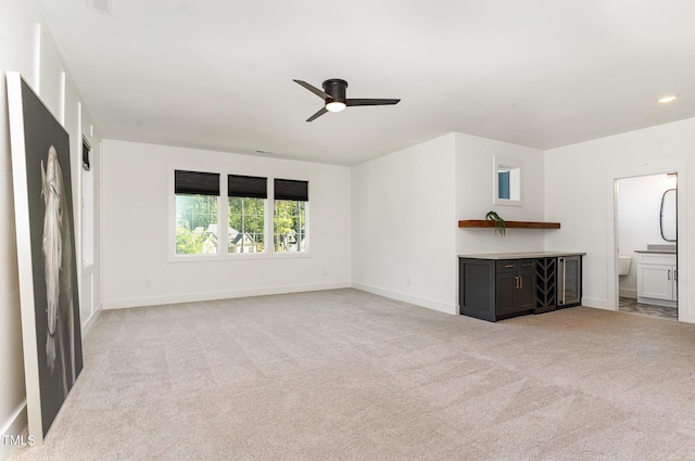 unfurnished living room featuring ceiling fan, light colored carpet, and baseboards