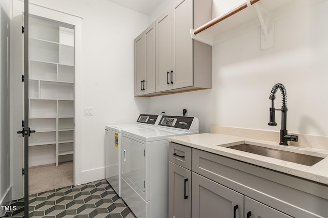 washroom with dark carpet, dark tile patterned floors, separate washer and dryer, a sink, and cabinet space