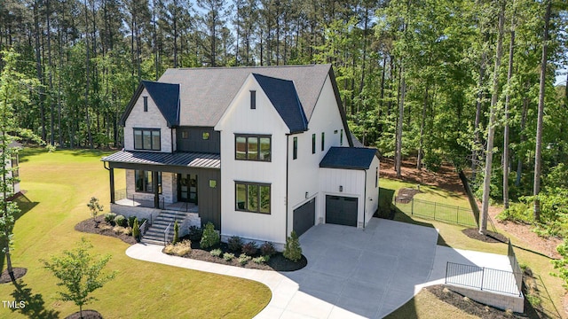 modern farmhouse style home with a front lawn, covered porch, driveway, and a standing seam roof