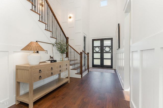entryway featuring french doors, dark wood-style flooring, a towering ceiling, and stairway