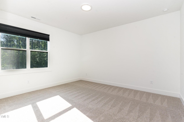 unfurnished room with visible vents, carpet, and baseboards