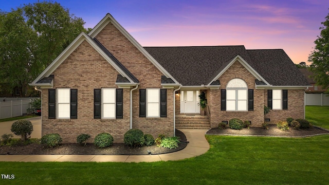 ranch-style home with brick siding, a front lawn, roof with shingles, and fence