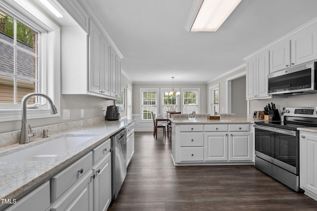 kitchen with crown molding, appliances with stainless steel finishes, a sink, a chandelier, and white cabinetry