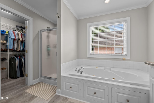 full bathroom featuring crown molding, a tub with jets, a shower stall, wood finished floors, and a spacious closet