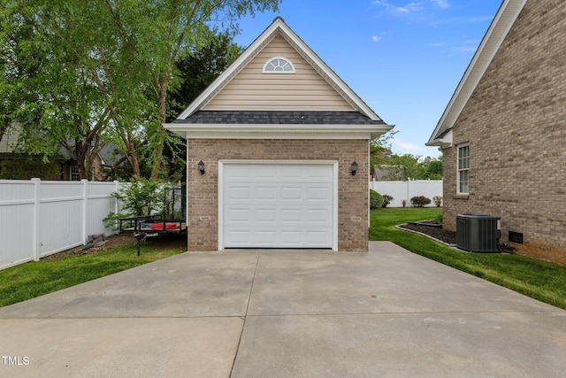 detached garage featuring fence, driveway, and cooling unit