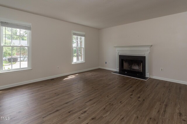 805 Penncross Dr, Raleigh, NC 27610 - unfurnished living room with dark wood-style floors, a fireplace with raised hearth, and baseboards