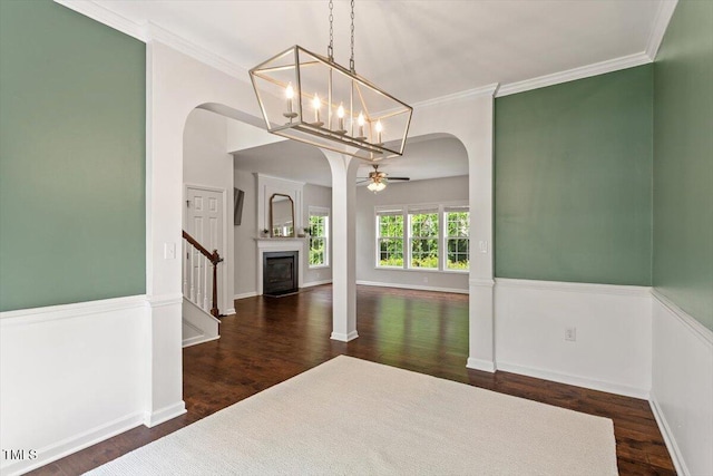 unfurnished dining area with arched walkways, a ceiling fan, wood finished floors, and ornamental molding