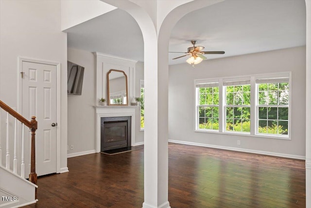 unfurnished living room with wood-type flooring, baseboards, ceiling fan, stairway, and a premium fireplace