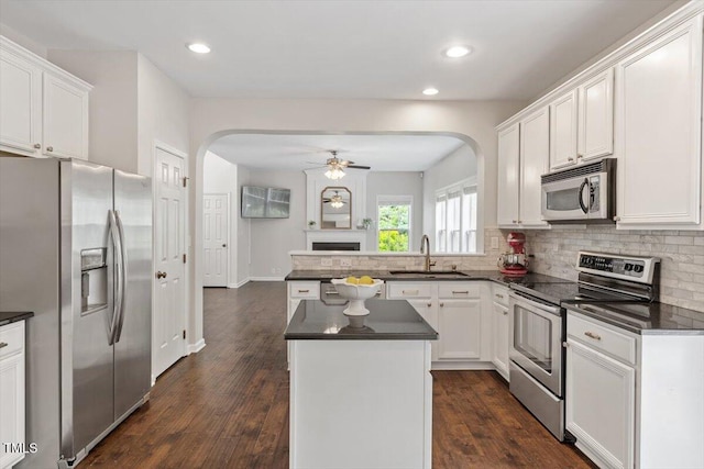 kitchen featuring a sink, appliances with stainless steel finishes, a ceiling fan, and arched walkways