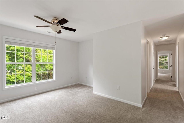carpeted empty room featuring baseboards and ceiling fan