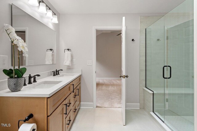 bathroom featuring double vanity, baseboards, a shower stall, and a sink