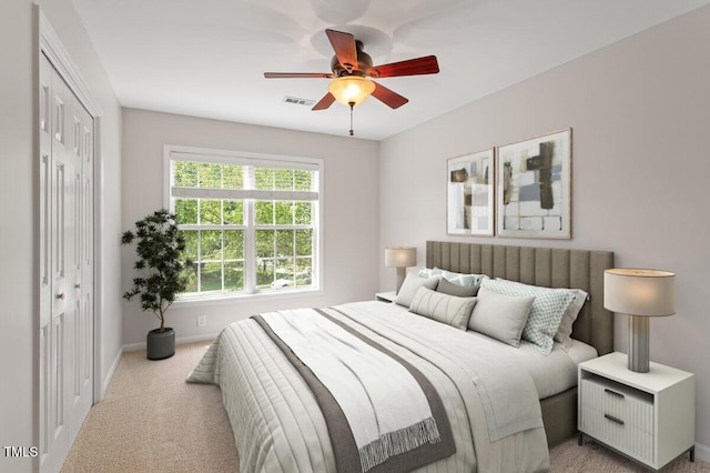 bedroom with a closet, visible vents, light carpet, baseboards, and a ceiling fan