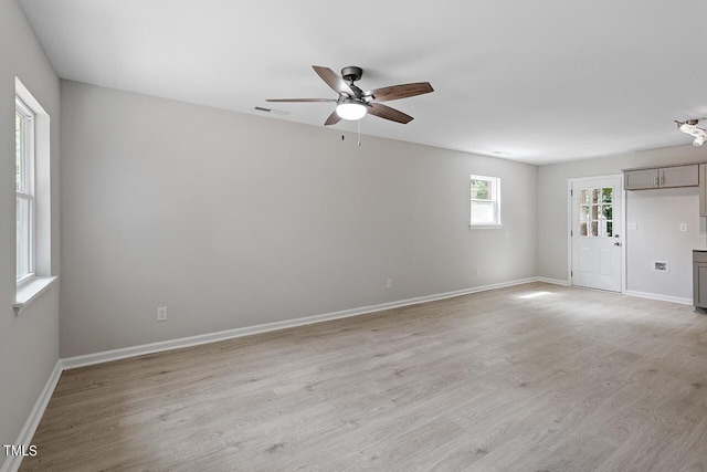 spare room featuring light wood-type flooring, visible vents, a ceiling fan, and baseboards