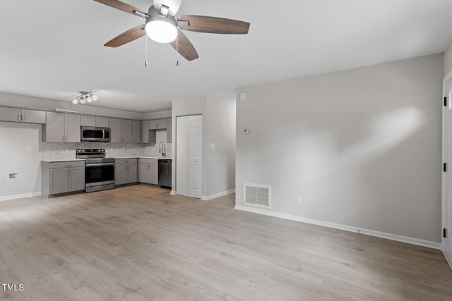 kitchen with baseboards, appliances with stainless steel finishes, gray cabinetry, and visible vents