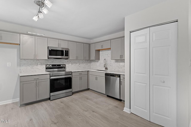 kitchen with stainless steel appliances, gray cabinetry, and a sink