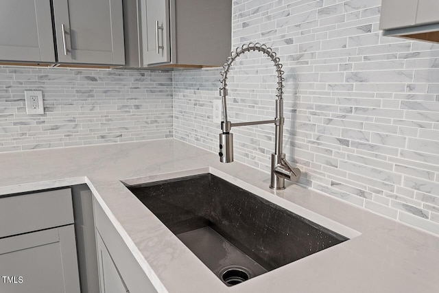 kitchen with tasteful backsplash, gray cabinetry, and a sink