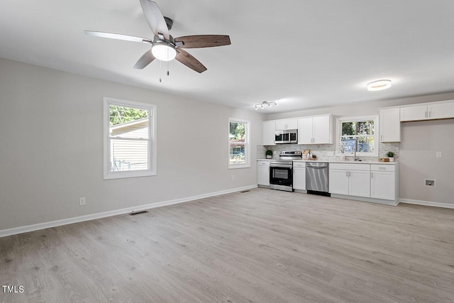 kitchen with a sink, a wealth of natural light, light wood-style flooring, and stainless steel appliances