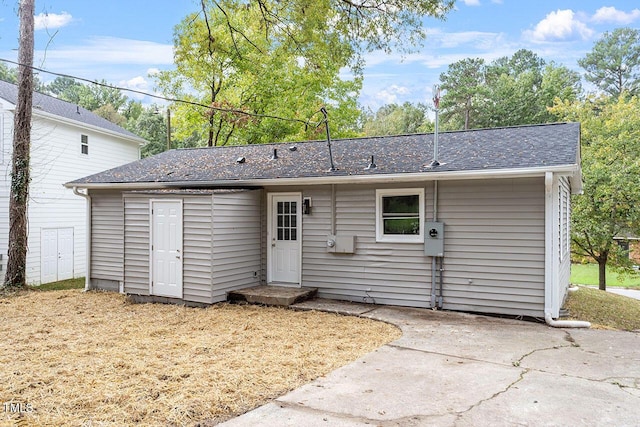 rear view of house featuring a patio and a shingled roof