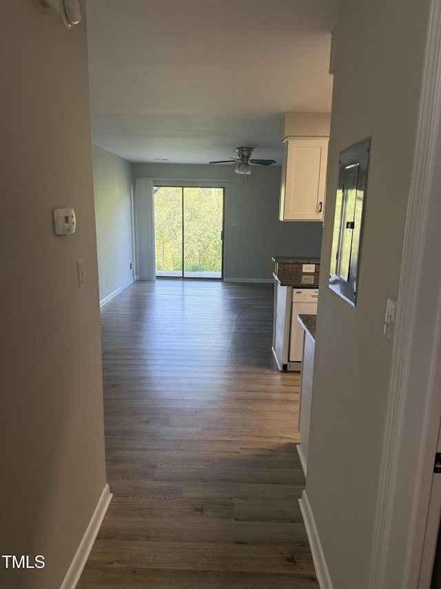corridor with dark wood-type flooring and baseboards