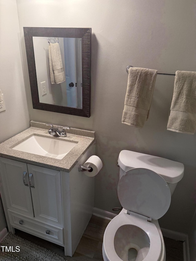 bathroom featuring baseboards, toilet, and vanity