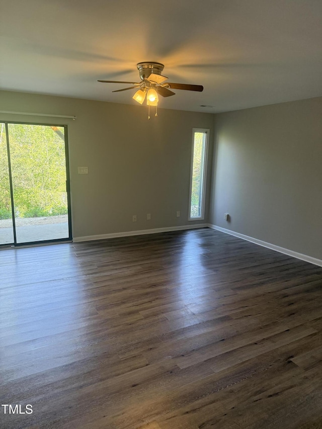 unfurnished room with baseboards, ceiling fan, and dark wood-style flooring