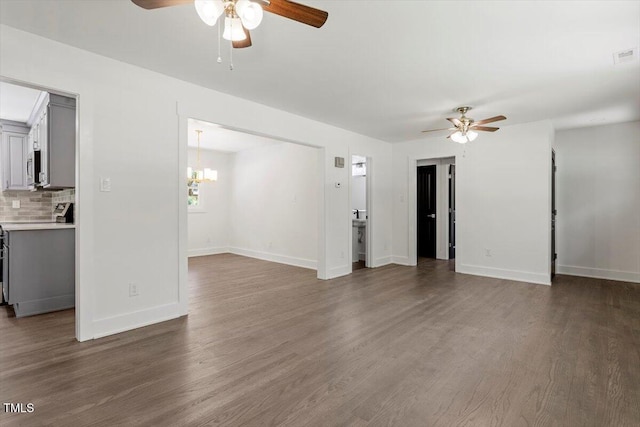 unfurnished living room featuring baseboards, ceiling fan with notable chandelier, and wood finished floors