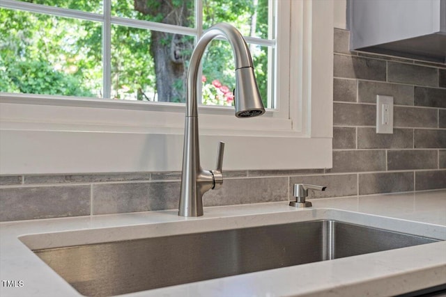 interior details featuring a sink, decorative backsplash, and light stone countertops