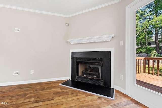interior details with crown molding, a fireplace with raised hearth, baseboards, and wood finished floors
