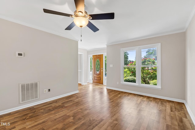 spare room with visible vents, baseboards, crown molding, and wood finished floors