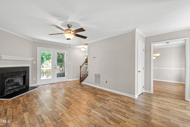 unfurnished living room with visible vents, ornamental molding, stairs, and wood finished floors