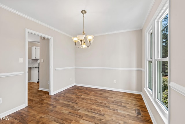 empty room featuring a chandelier, baseboards, visible vents, and wood finished floors