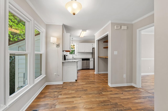 kitchen featuring backsplash, wood finished floors, dishwasher, baseboards, and white cabinets